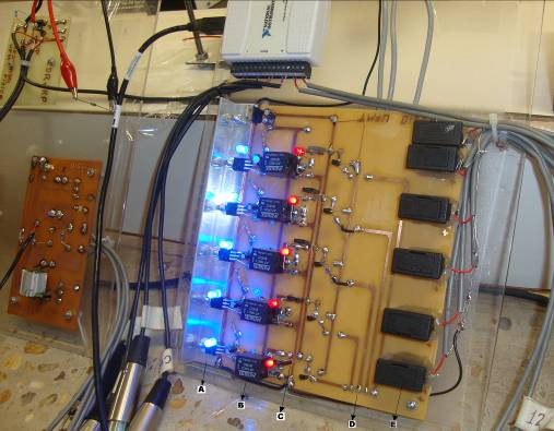 Placa denominada FONTES. (A) Dissipador de calor com os reguladores de tensão, (B) relés, (C) transistores, (D) entrada do sinal do DAQ e (E) porta fusíveis para cada saída de tensão.  